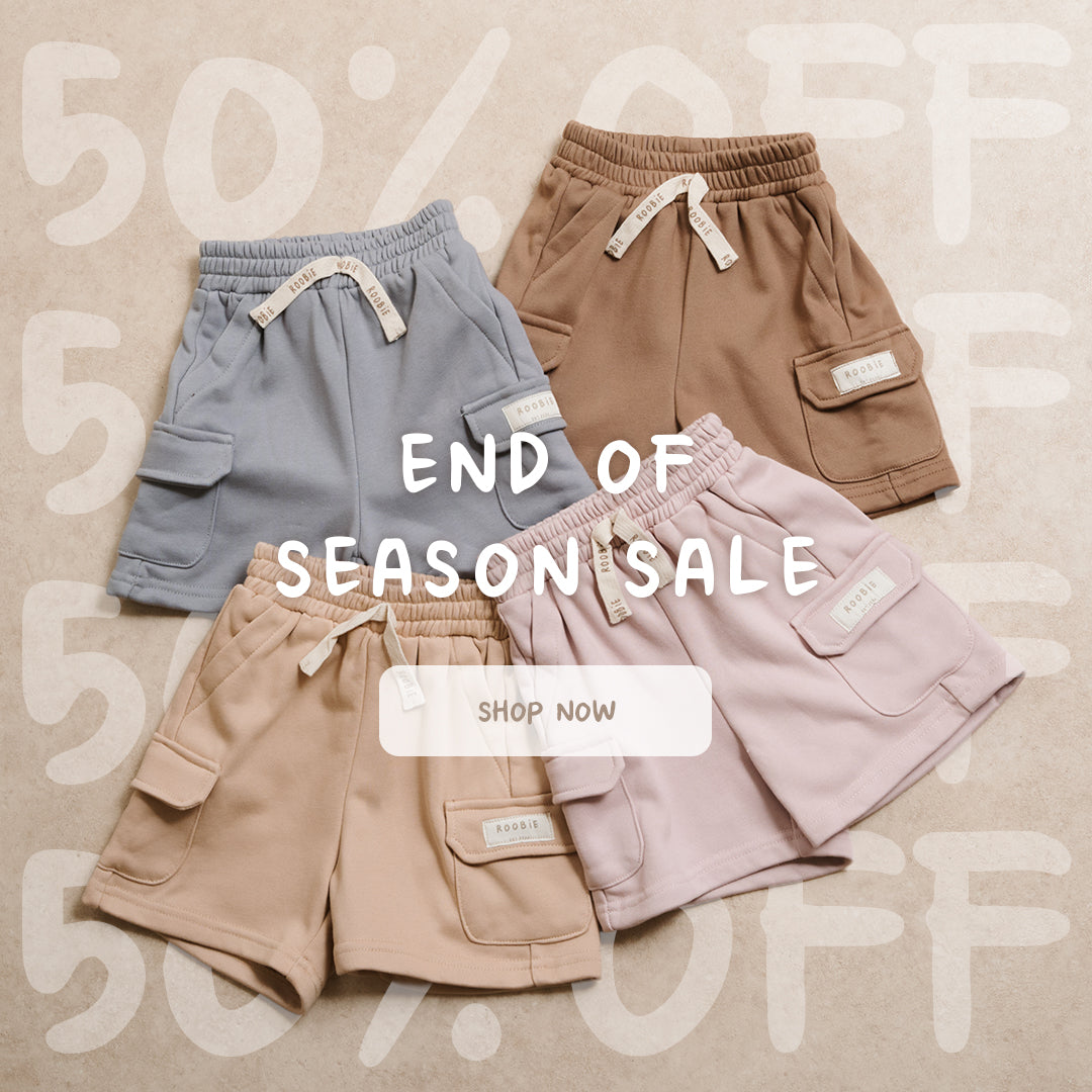 Four pairs of children's Cargo Shorts in light blue, brown, beige, and light pink are arranged on a beige background.