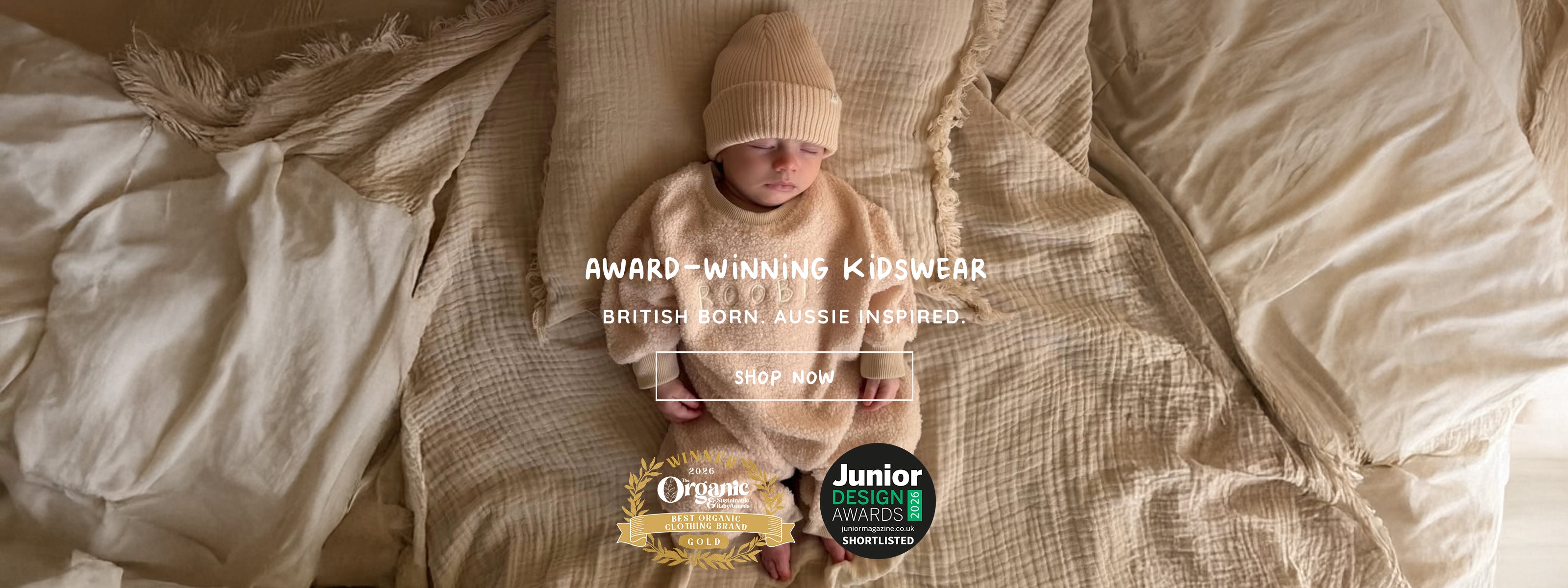 Sleeping newborn wearing ROOBiE's oversized beige Teddy One-Piece romper and knit 100% Cotton Ribbed Beanie on cream muslin bedding
