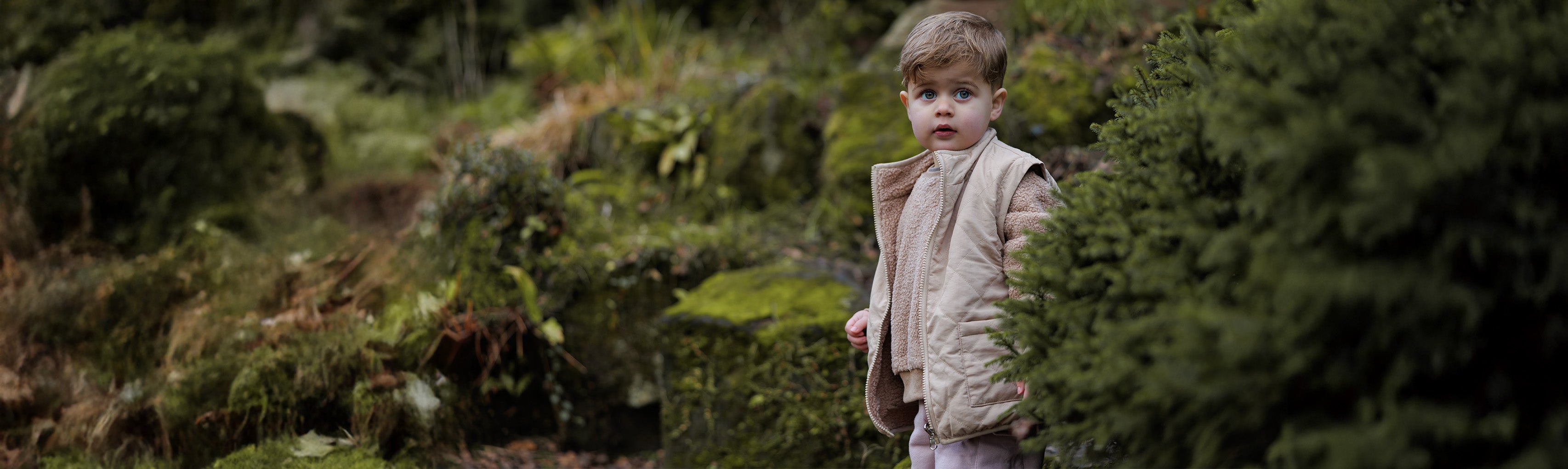Child standing in a winter forest with in cosy winter teddy coat, jumper and trousers