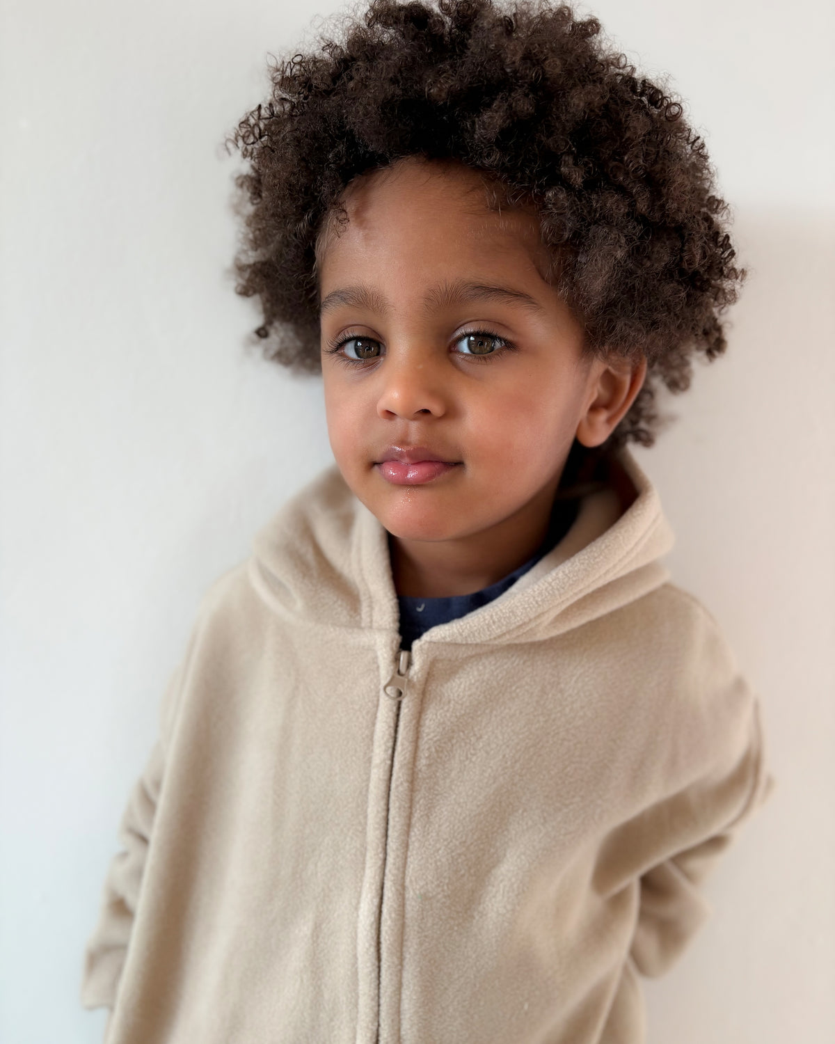 Child wearing a beige soft touch fleece zip up cosy winter hoodie against a plain background