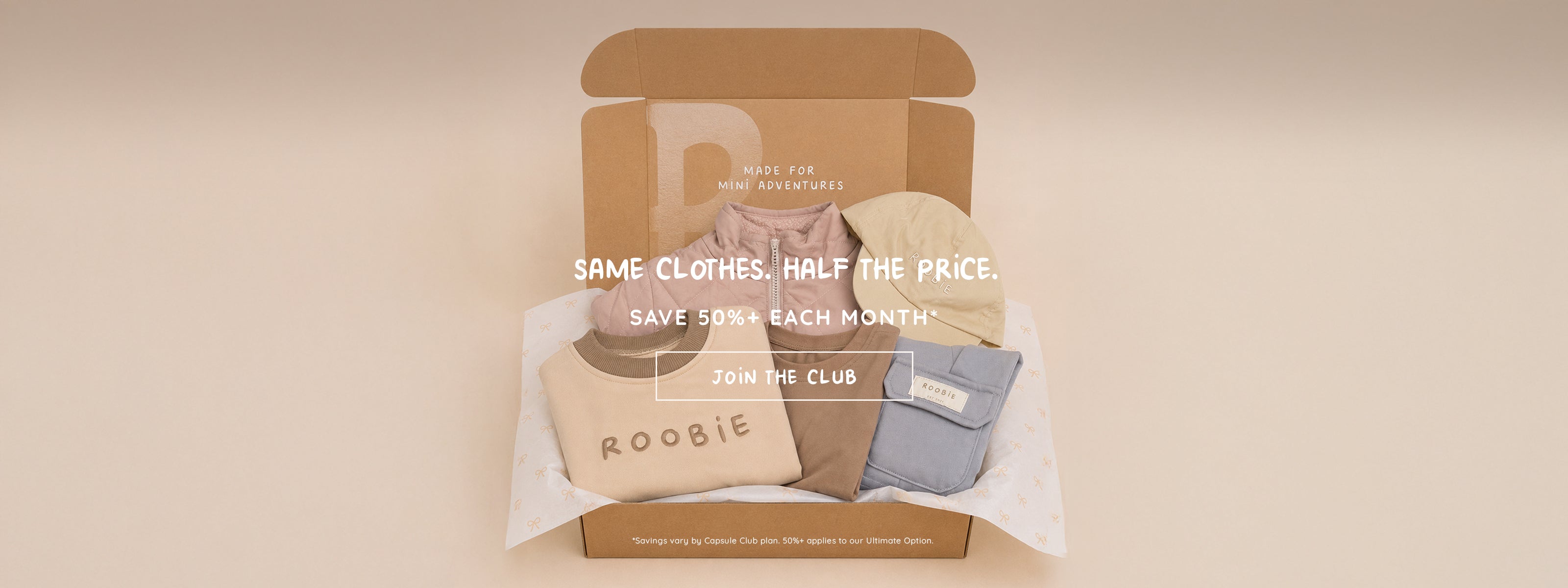 Open ROOBiE box showing a folded capsule wardrobe: quilted jacket, embroidered ROOBiE sweatshirt, joggers, cargo pants and a bucket hat in neutral tones.