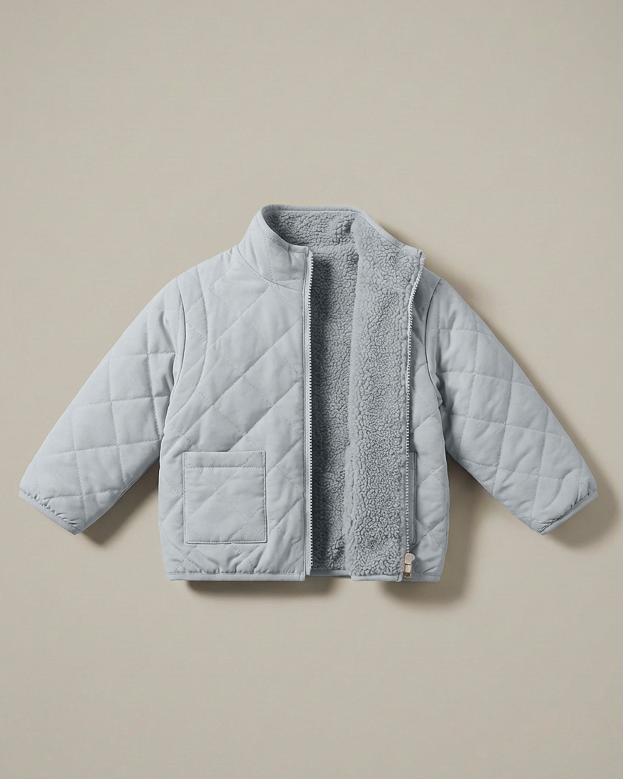 A light gray-blue 4-in-1 reversible quilted jacket with a soft, textured matching fleece lining, displayed flat against a solid beige background.