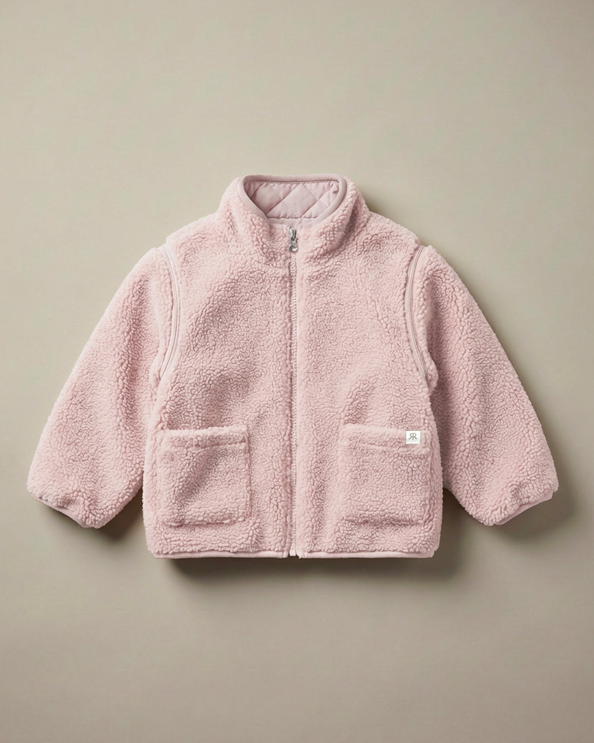 A light pink teddy fleece 4-in-1 reversible zip-up jacket with a stand-up collar and two front patch pockets, laid flat on a neutral beige background.