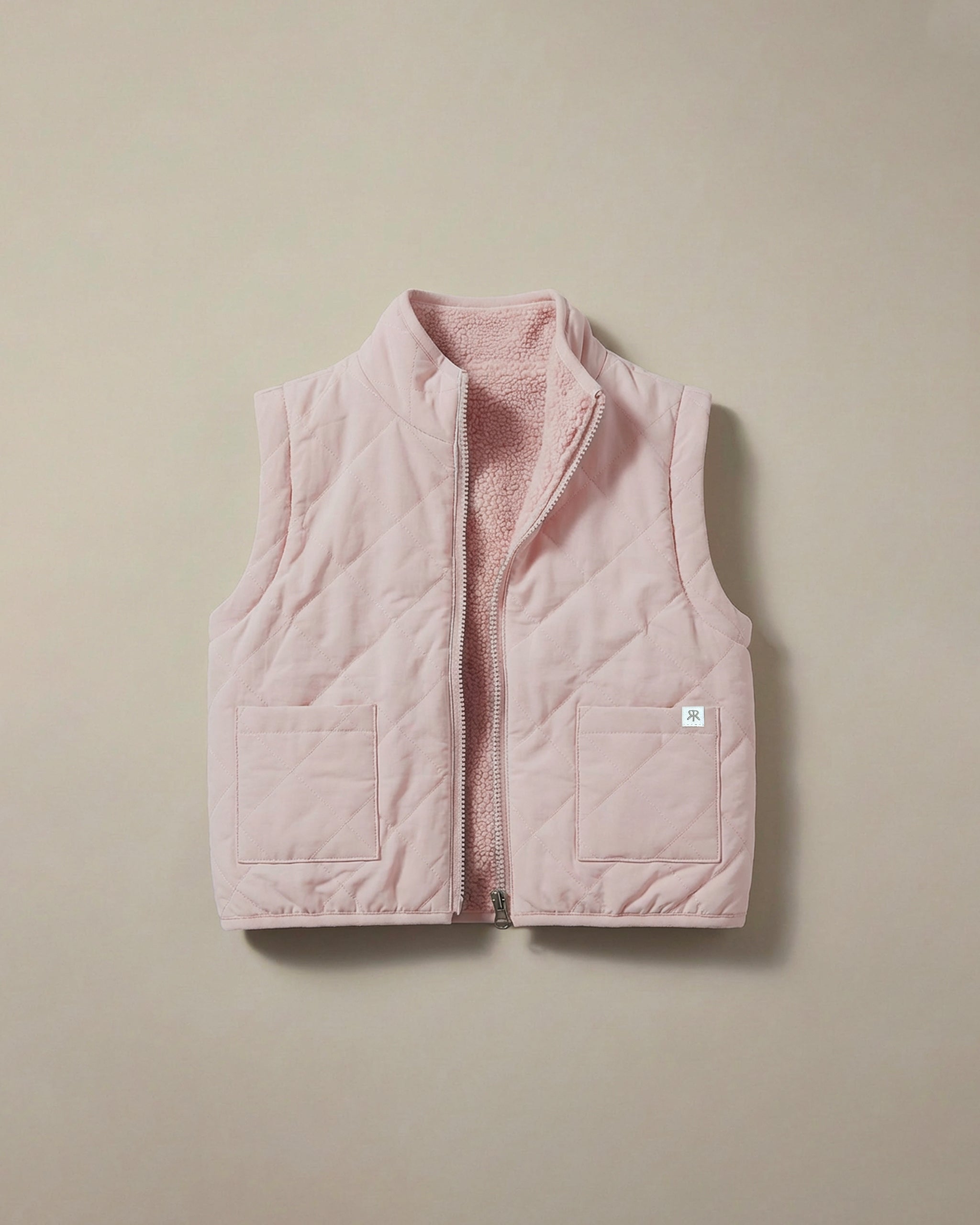 A light pink quilted 4-in-1 reversible teddy coat/gilet with a soft fleece lining, displayed flat against a neutral beige background.