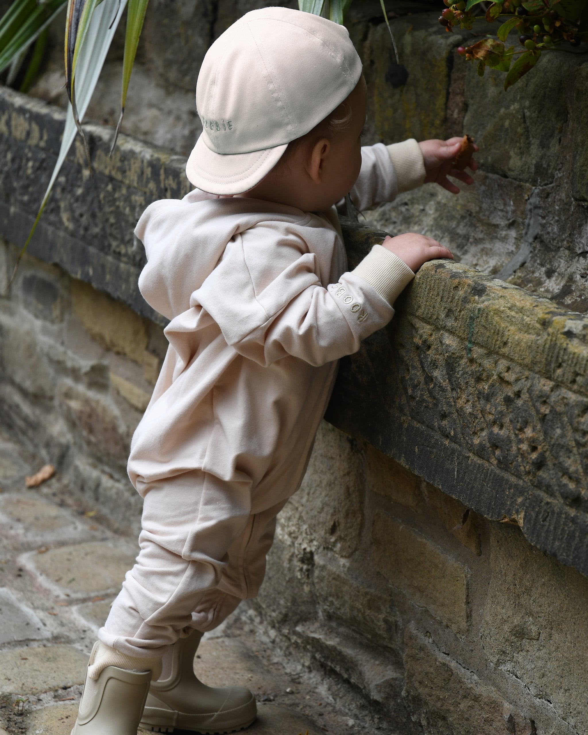 ROOBiE toddler jumpsuit in MACADAMiA MiLK – neutral beige hooded one-piece, designed for a capsule wardrobe