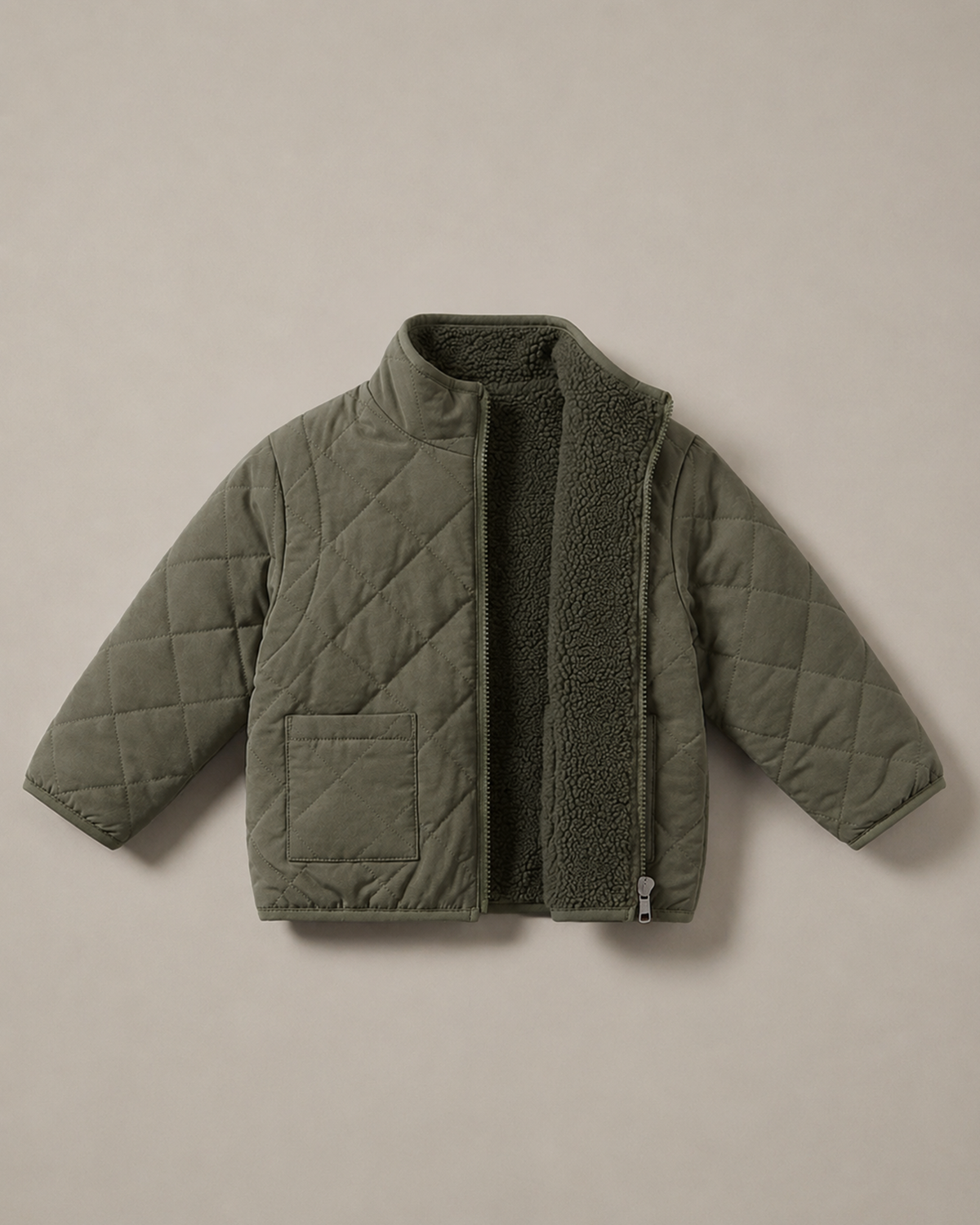 A quilted jacket in a muted sage-olive green color, featuring a diamond-quilted exterior and a plush teddy fleece interior lining, laid flat against a neutral beige background.