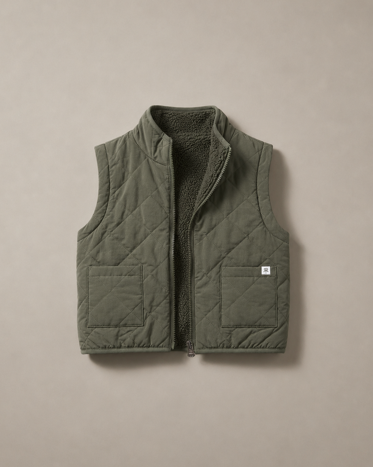 A sage olive quilted puffer vest with a soft teddy fleece lining, shown flat against a neutral beige background.