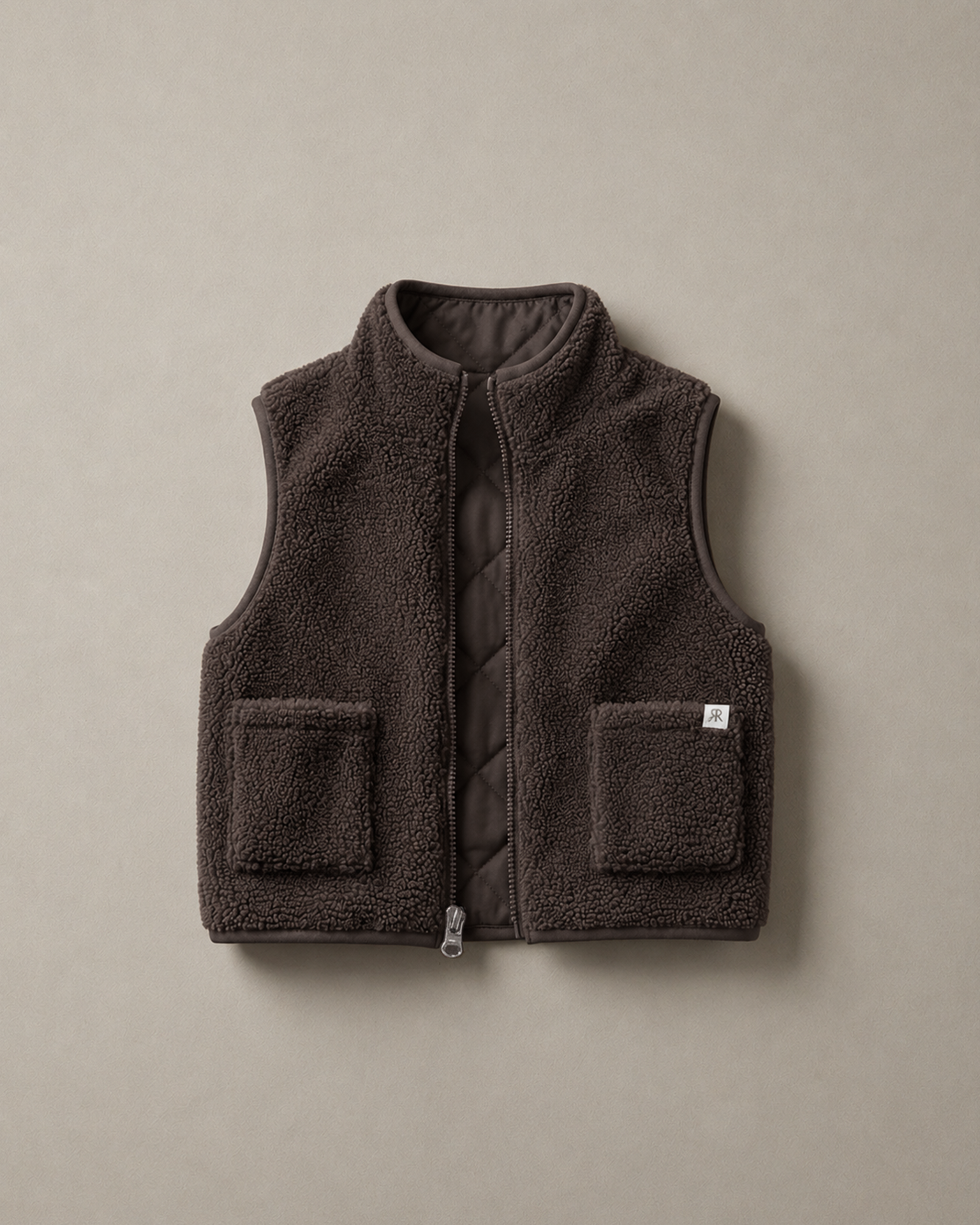 A dark brown teddy fleece gilet with a quilted inner and two front patch pockets, displayed flat against a neutral taupe background.
