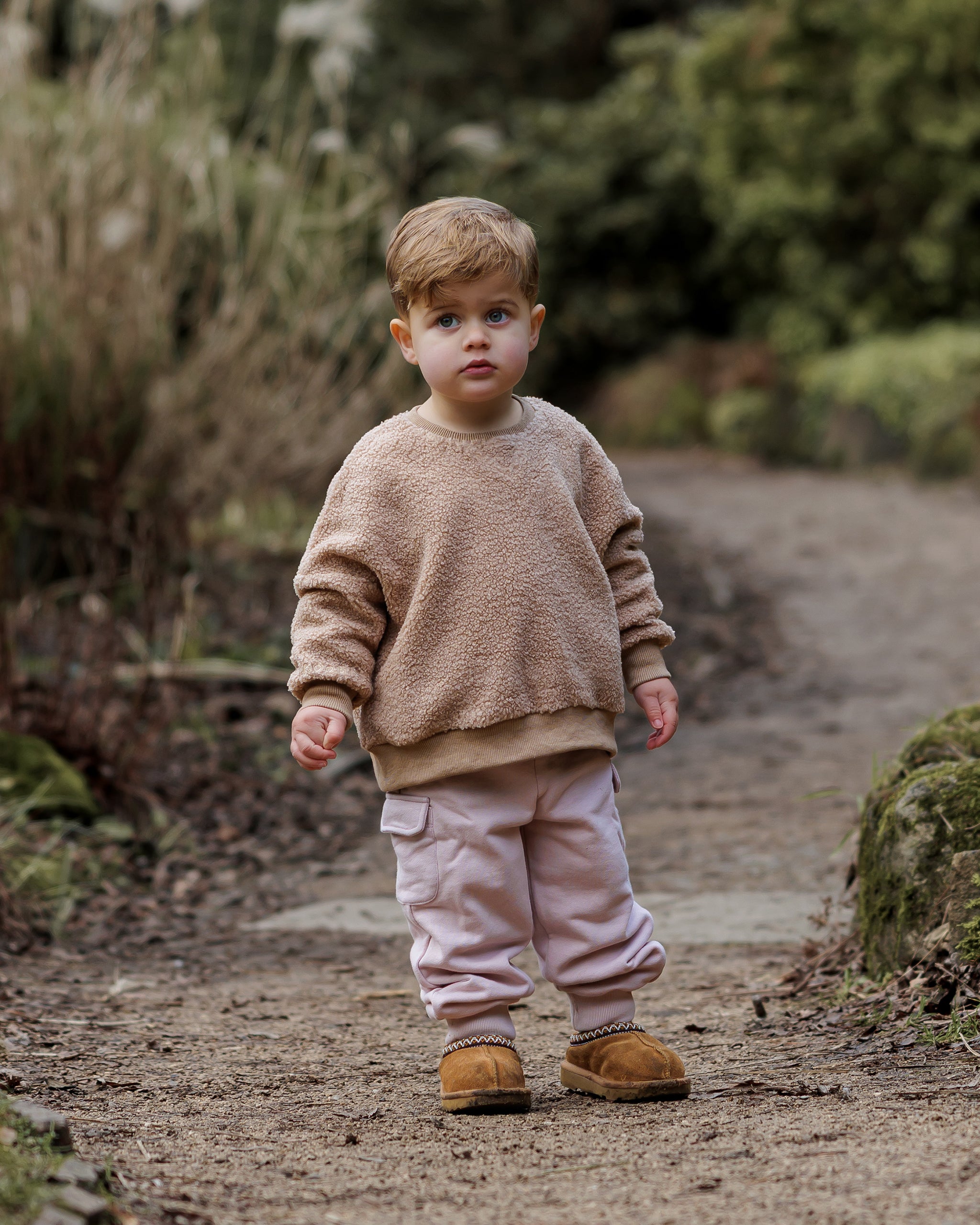 A warm brown teddy fleece jumper from ROOBiE, featuring soft teddy texture and oversized fit with pink cargo pants, photographed in a natural background.