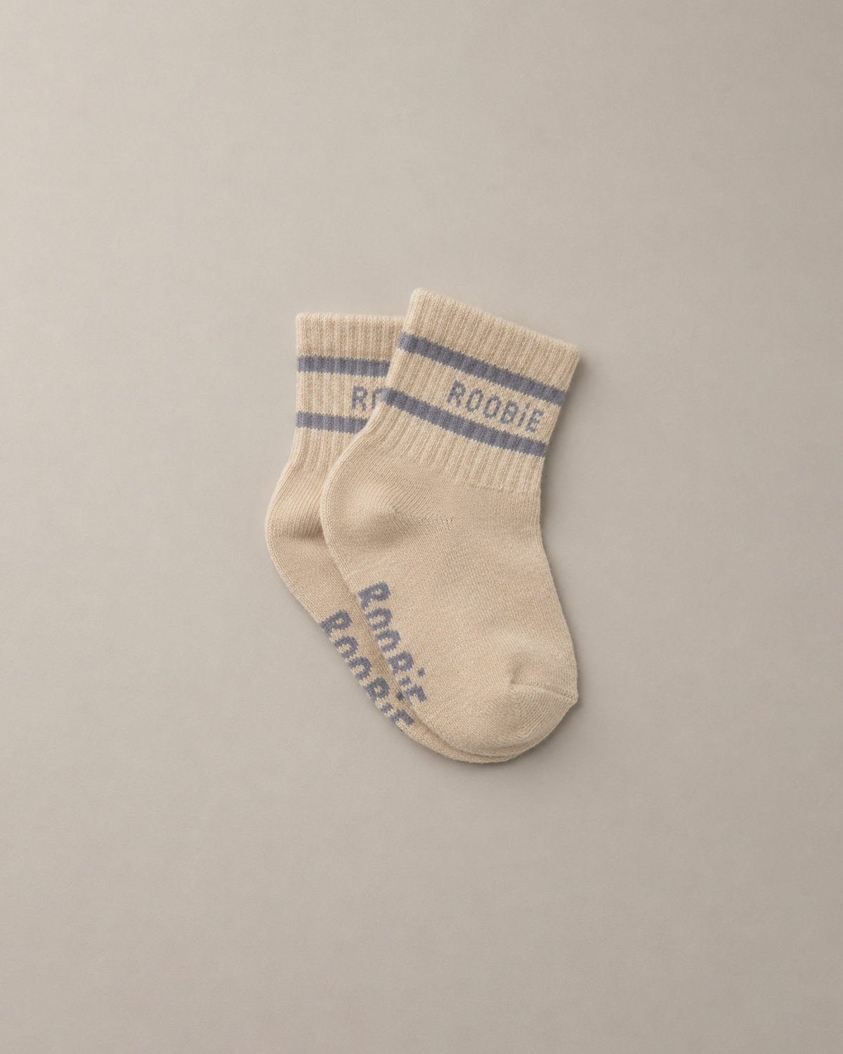 Pair of beige socks with blue-gray-purple stripes and 'ROOBiE' branding on a neutral beige background