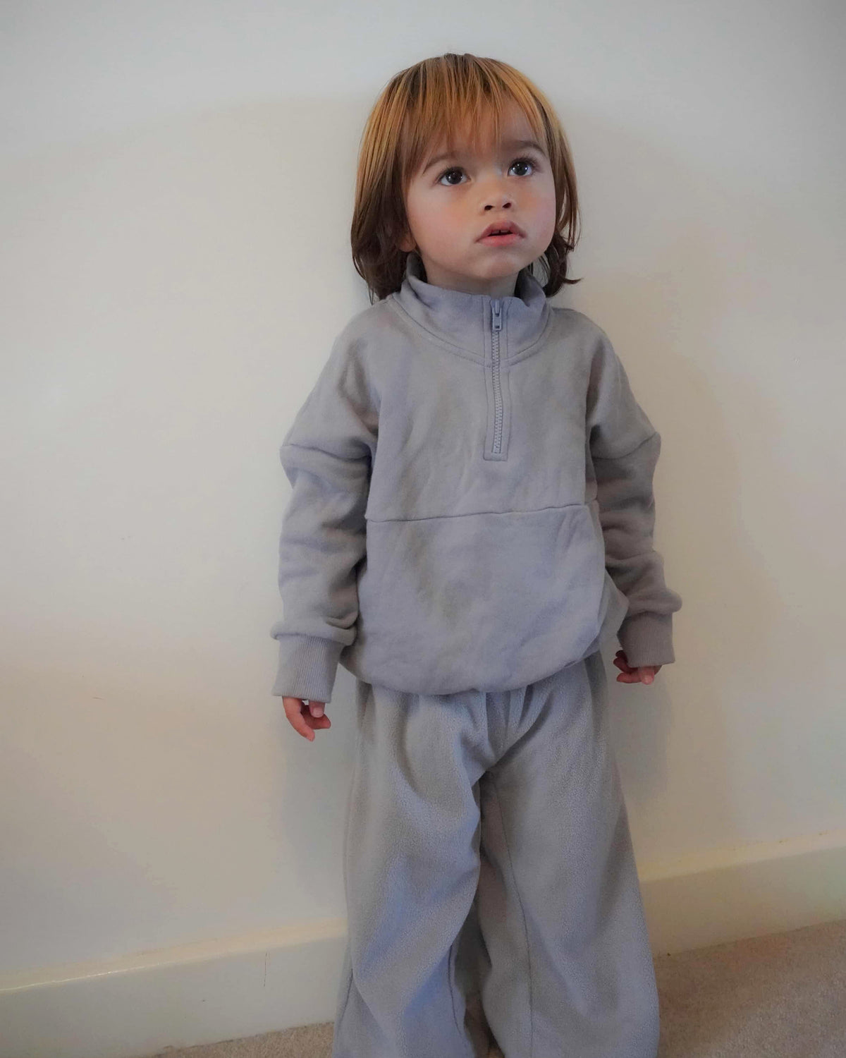 Child wearing a light blue fleece quarter zip jumper and wide leg jogger co-ord tracksuit against a plain background
