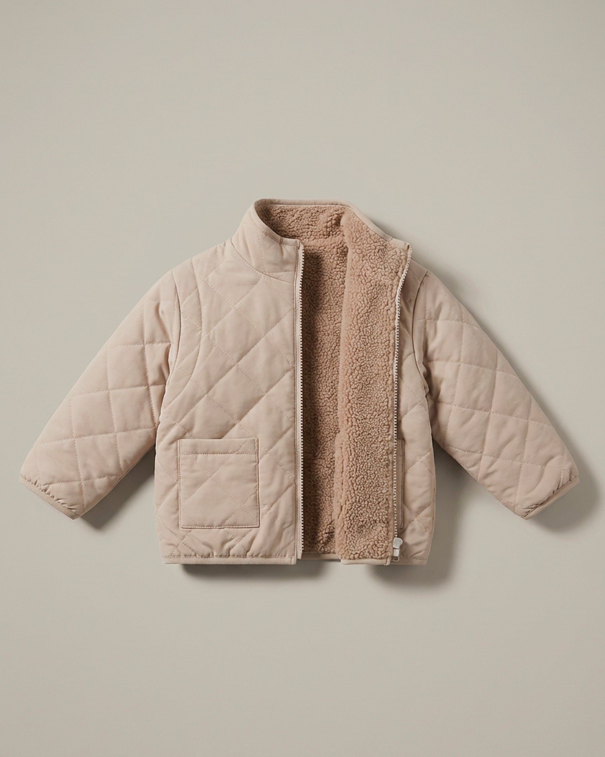 A neutral brown 4-in-1 reversible quilted jacket with a soft, textured matching fleece lining, displayed flat against a solid beige background.
