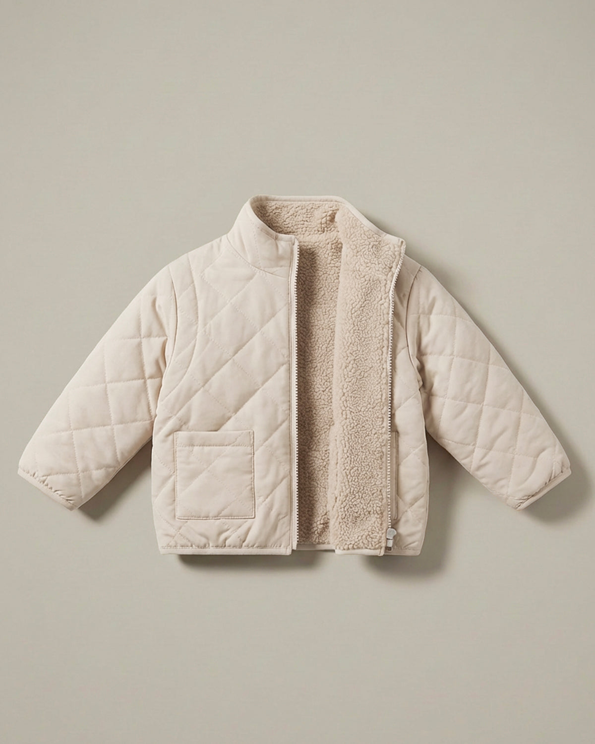 A neutral cream 4-in-1 reversible quilted jacket with a soft, textured matching fleece lining, displayed flat against a solid beige background.