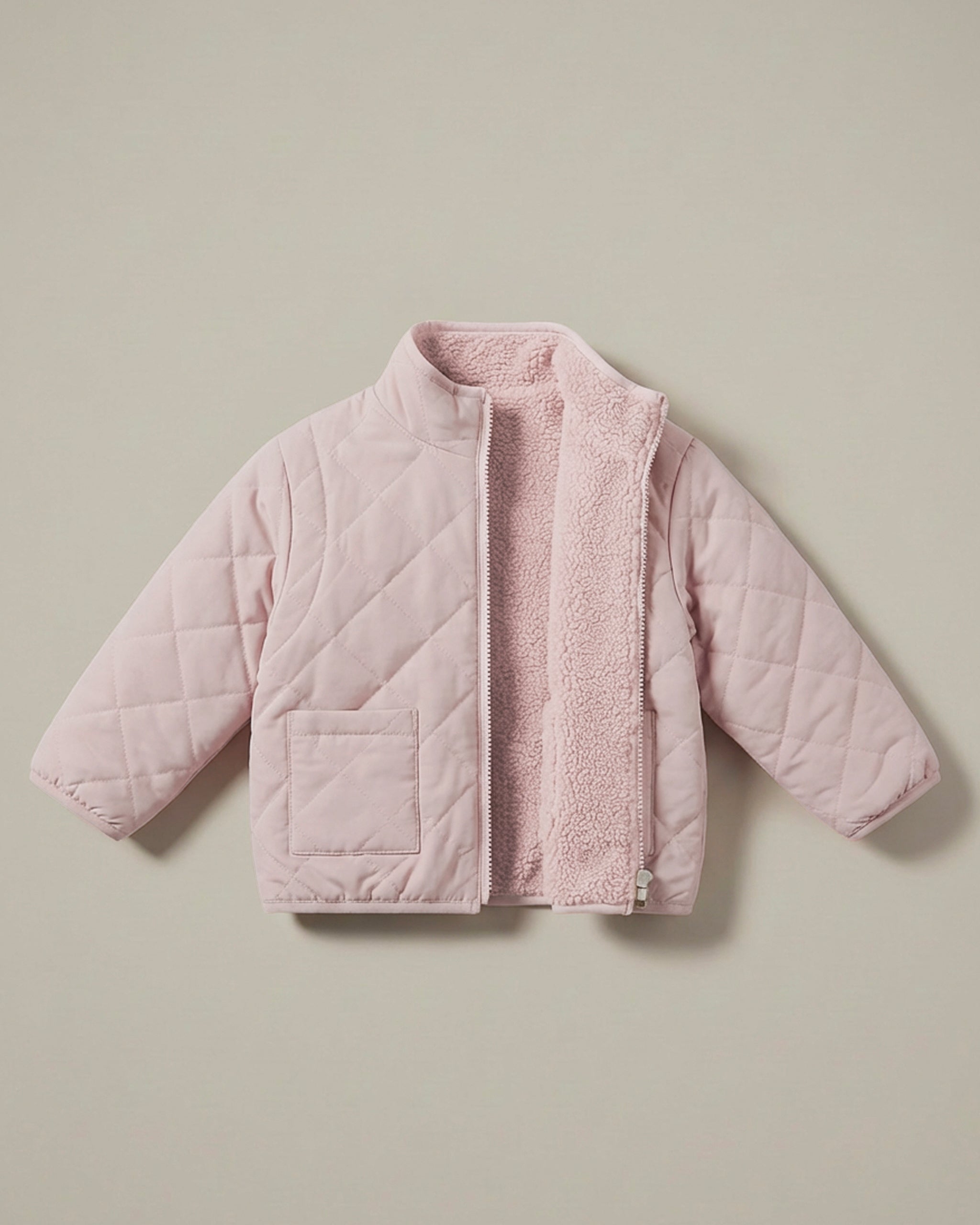 A light pink 4-in-1 reversible quilted jacket with a soft, textured matching fleece lining, displayed flat against a solid beige background.