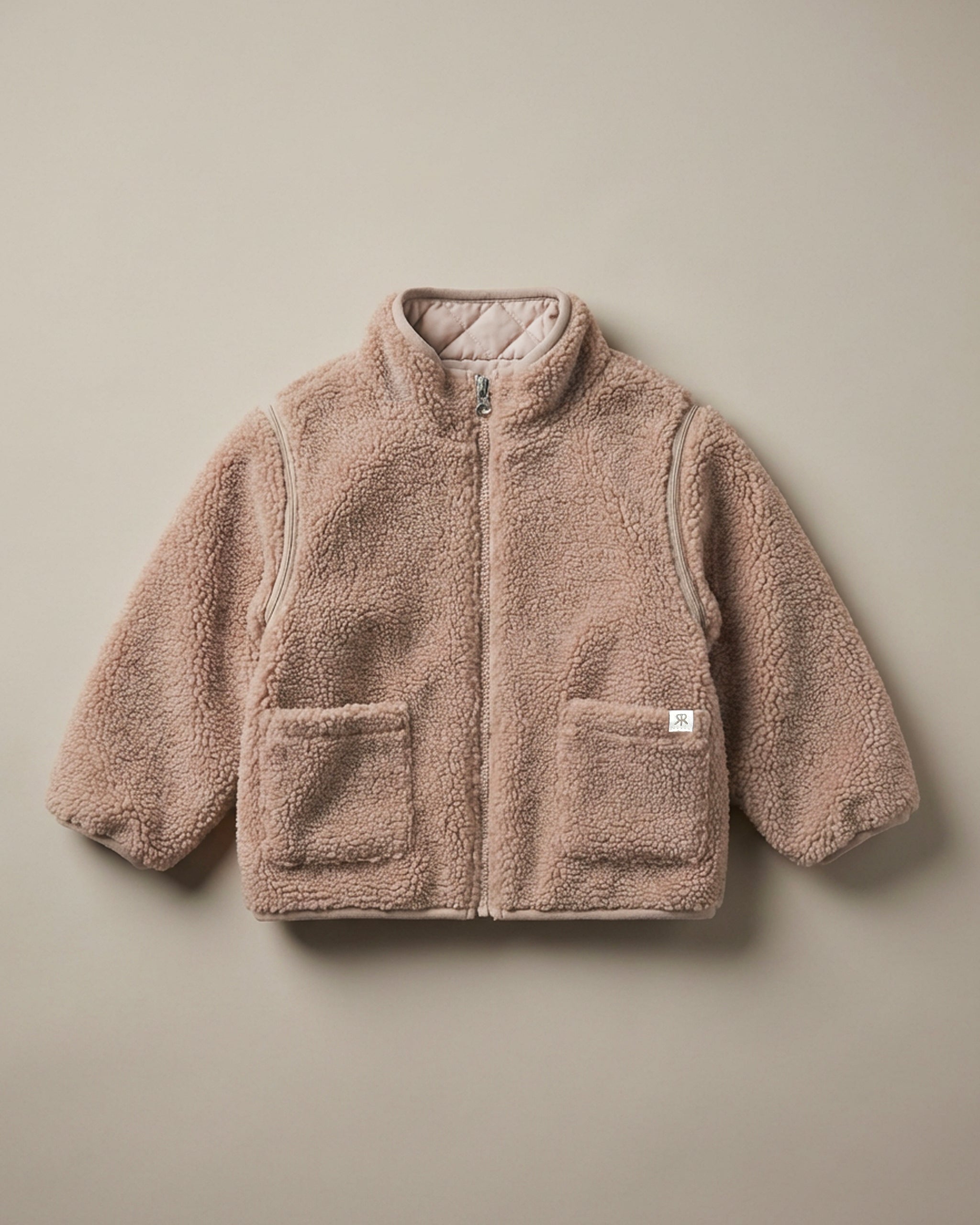 A neutral brown 4-in-1 reversible teddy fleece jacket with a soft, textured matching quilted lining, displayed flat against a solid beige background.