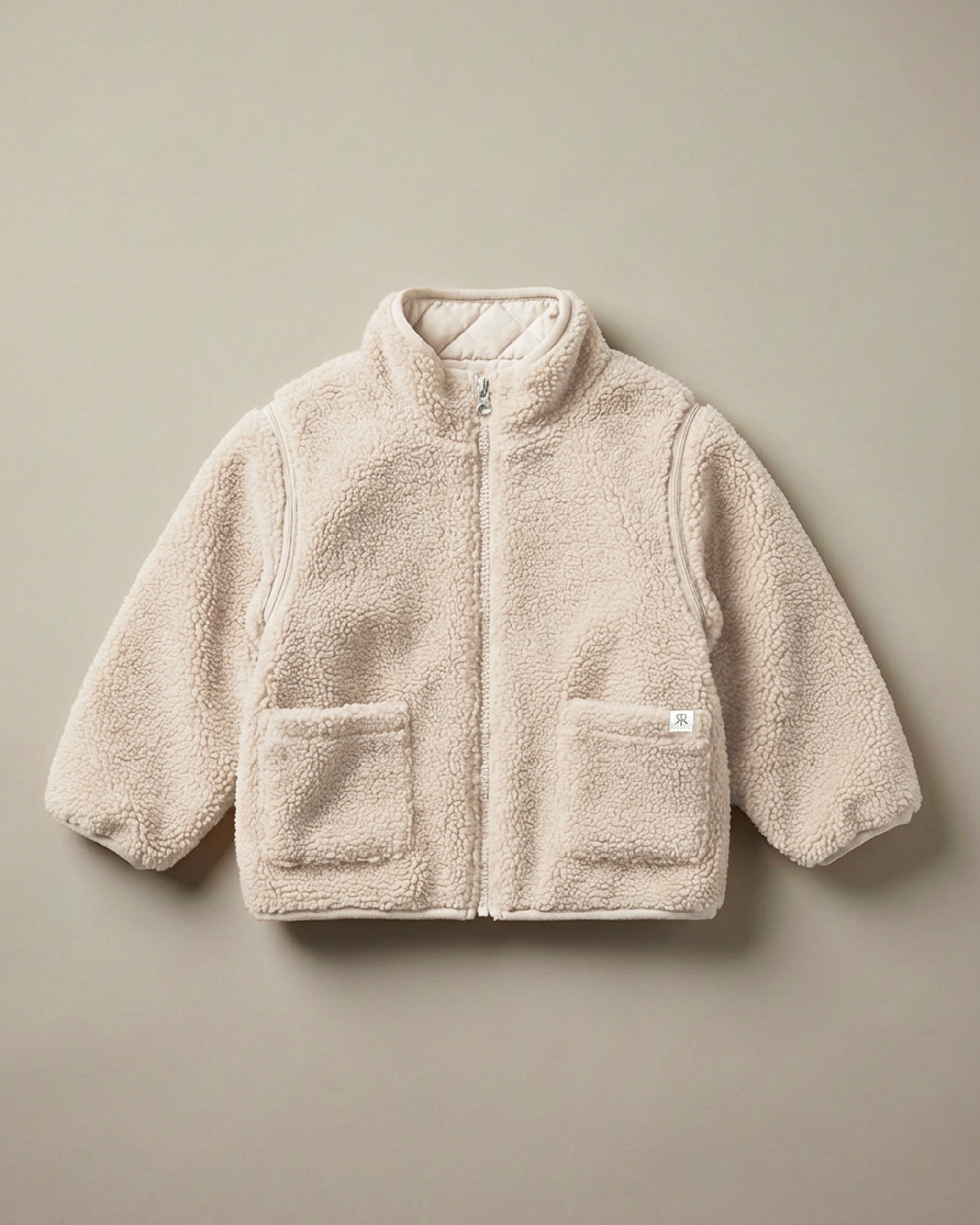 A neutral cream 4-in-1 reversible teddy coat with a soft, textured matching quilted lining, displayed flat against a solid beige background.