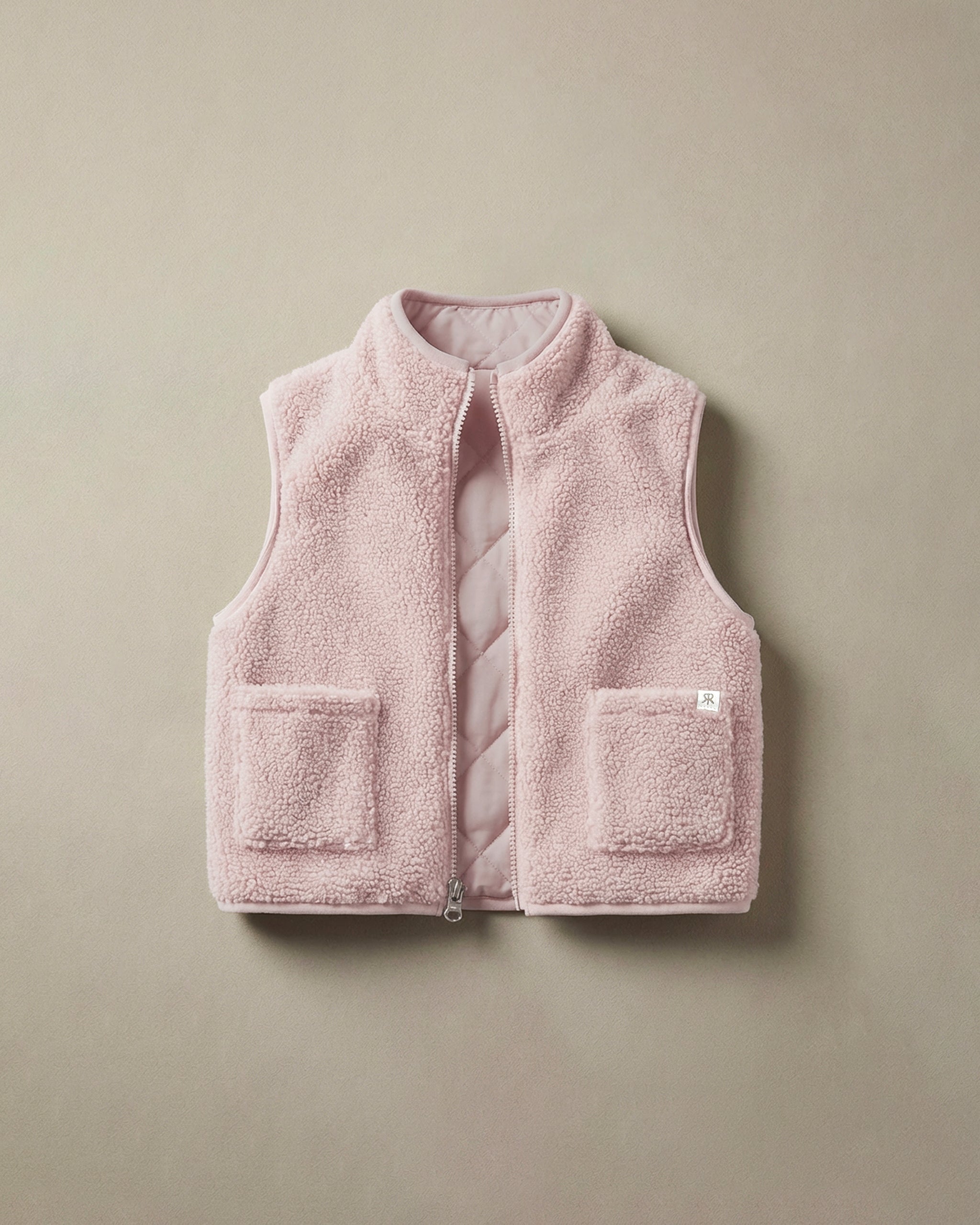 A light pink fleece teddy gilet with a quilted inner lining, featuring a stand-up collar, front zipper, and two front patch pockets, shown flat on a neutral beige background.