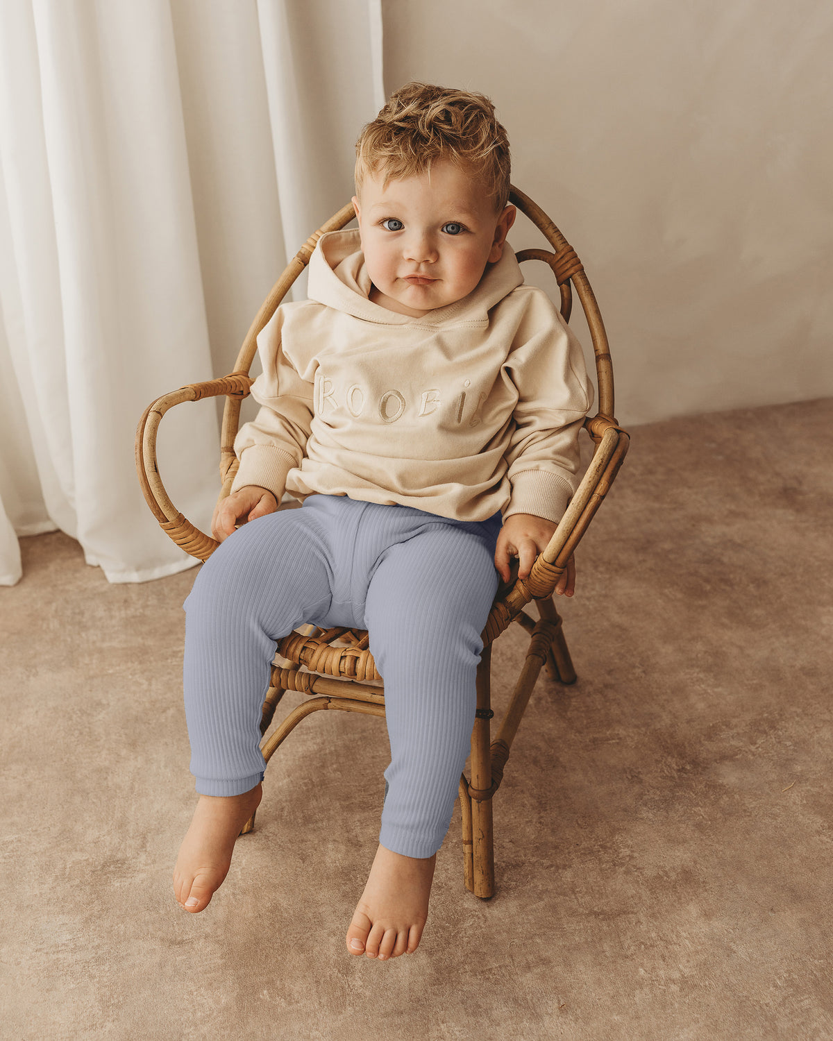 A toddler boy wearing light blue ribbed leggings from ROOBiE, featuring ribbed fabric and stretch fit, photographed against a neutral background.