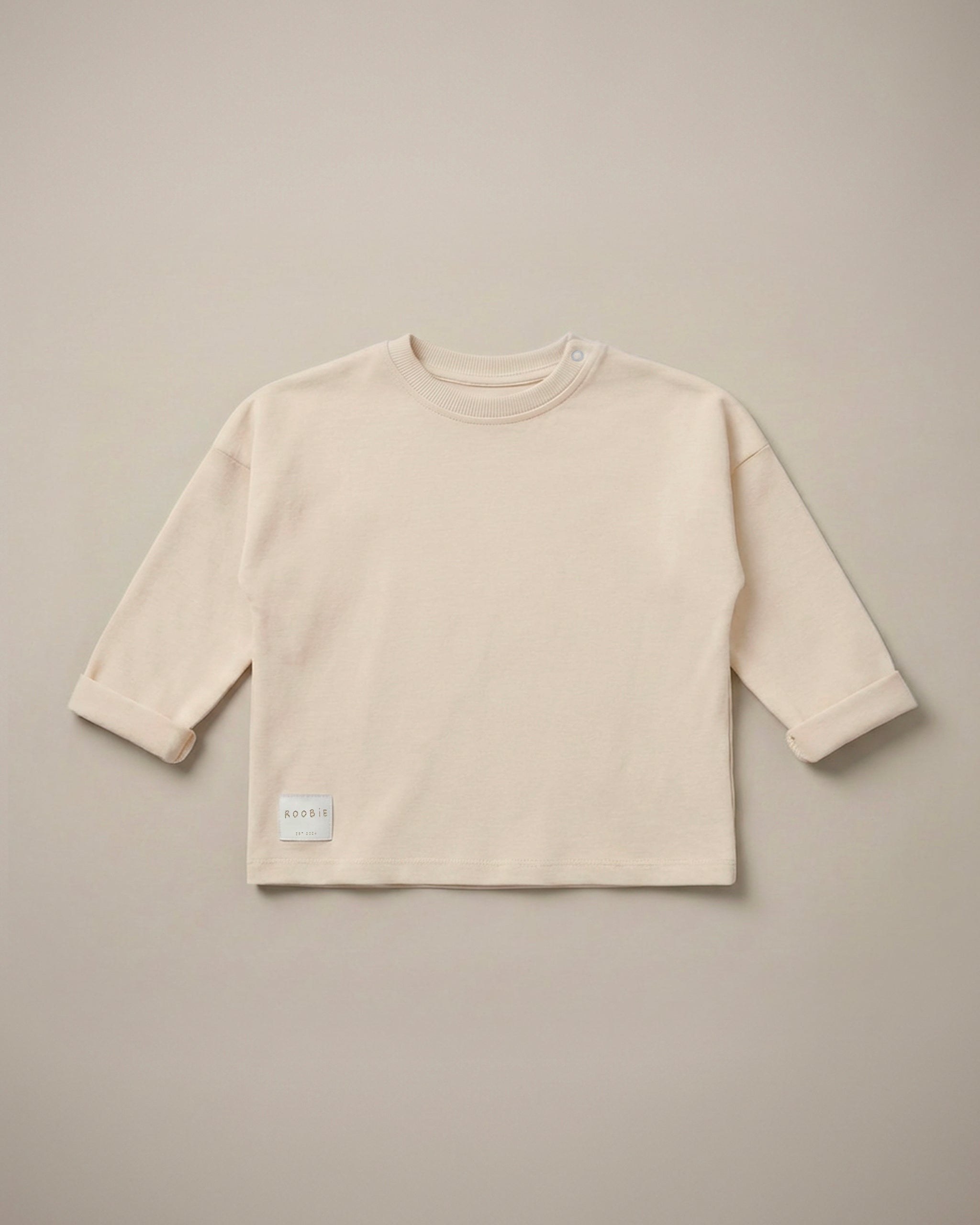 A cream long sleeve t-shirt from ROOBiE, featuring an oversized fit, photographed against a neutral background.