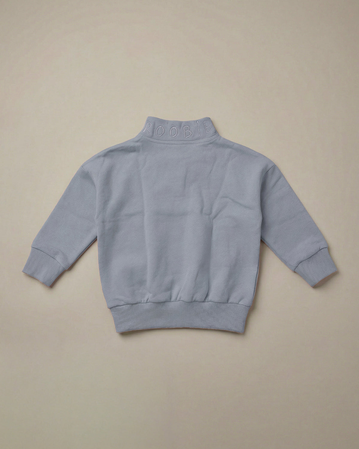 Light blue quarter-zip sweatshirt by ROOBiE, designed with an oversized fit, shown as a simple product flat lay.