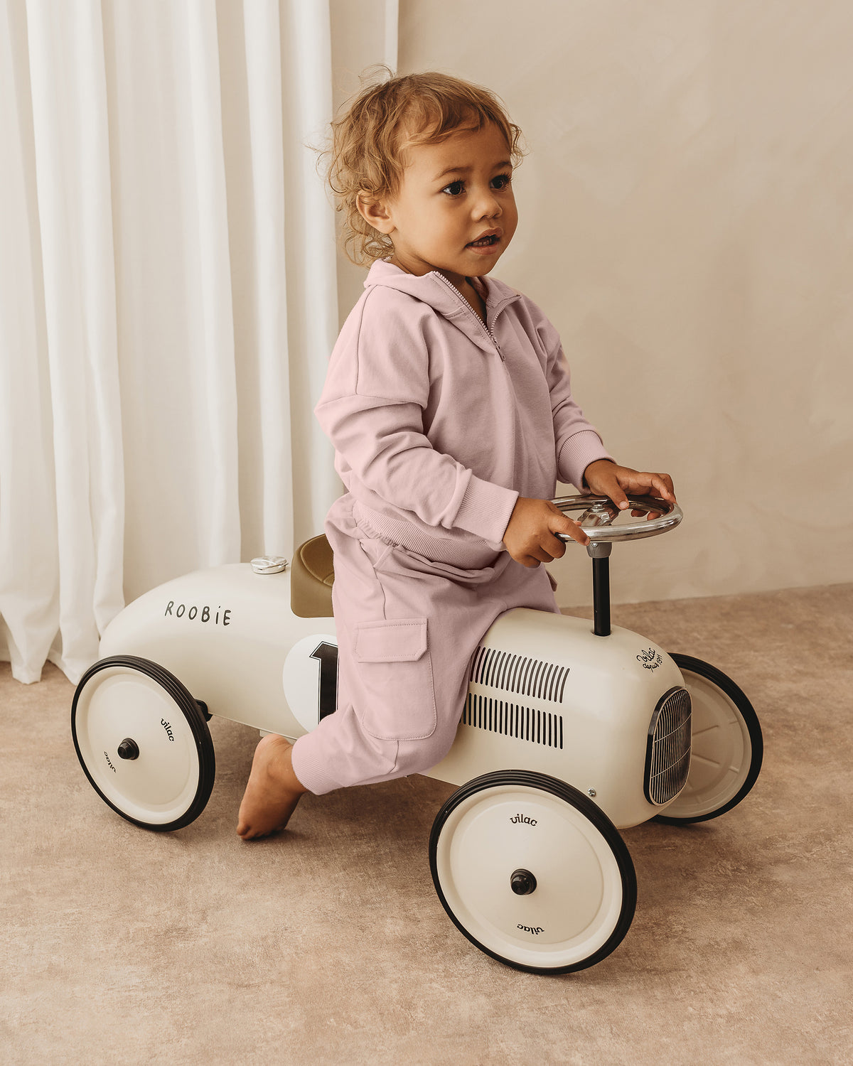Todder girl on a car wearing ROOBiE quarter-zip sweatshirt in soft pink, with quarter-zip neckline, oversized fit and long sleeves in a neutral studio setting.