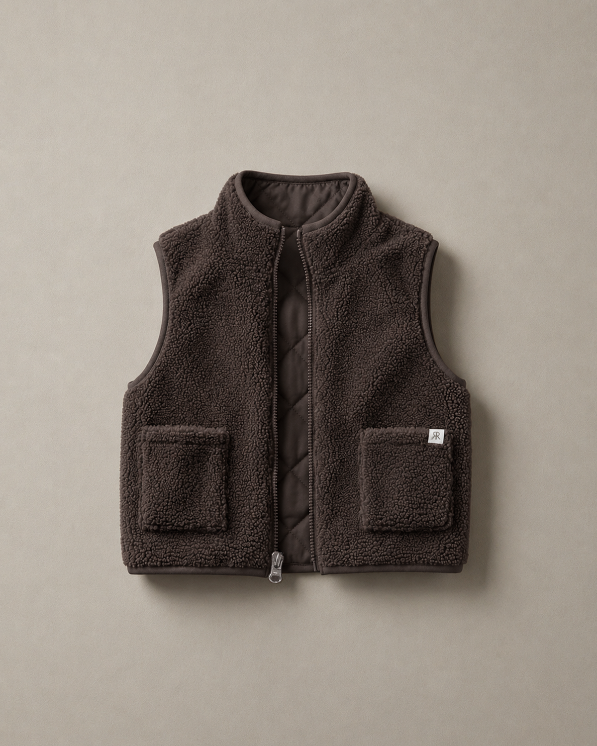 A dark brown teddy fleece gilet with a quilted inner and two front patch pockets, displayed flat against a neutral taupe background.
